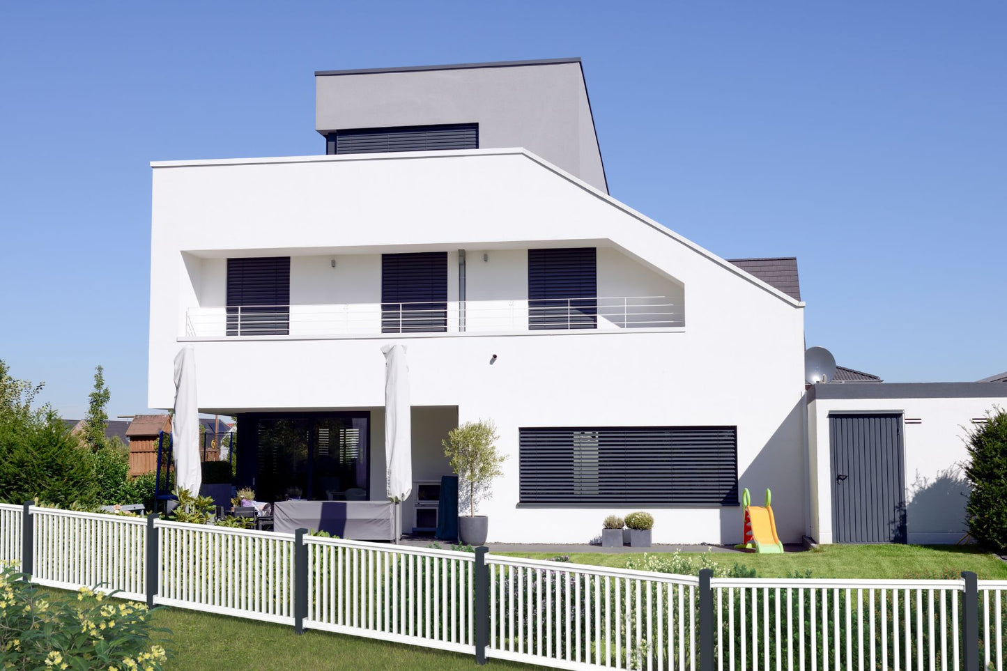 Railingzaun mit 35er Latte in weiß mit Pfosten in anthrazit - schräger Verlauf vor weißem Haus