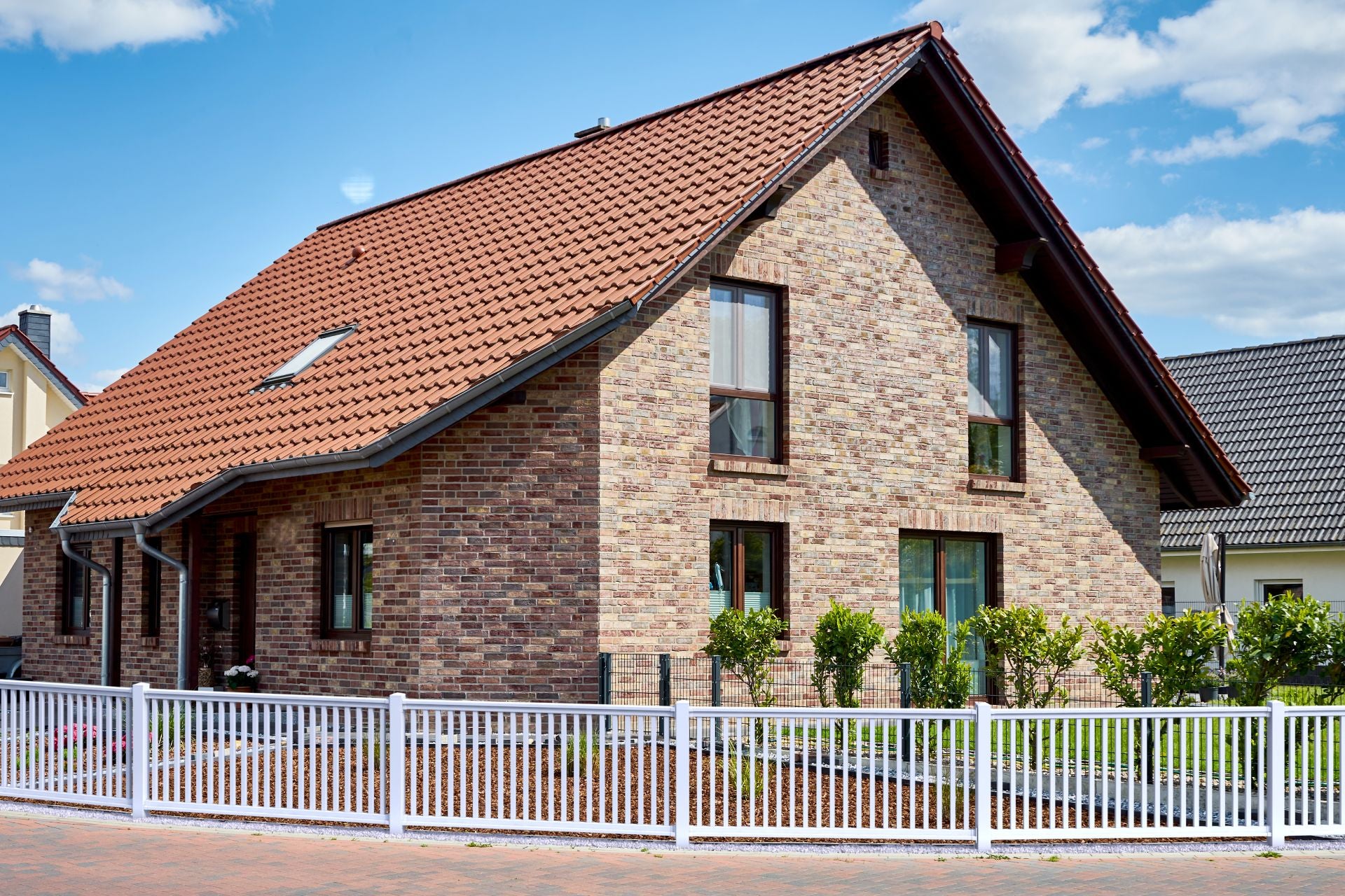 Railingzaun weiß mit 35er Latte und Pfosten anthrazit vor Haus mit Backstein Fassade