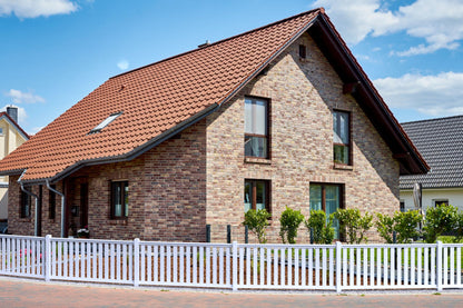 Railingzaun weiß mit 82er Latte und Pfosten anthrazit vor Haus mit Backstein Fassade